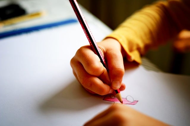 Lapsen käsi piirtämässä kuvaa paperille.